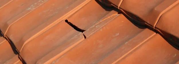 Tuile cassée sur une toiture, pouvant provoquer une infiltration d’eau. Dégâts de tempête sur toiture avec tuiles arrachées.